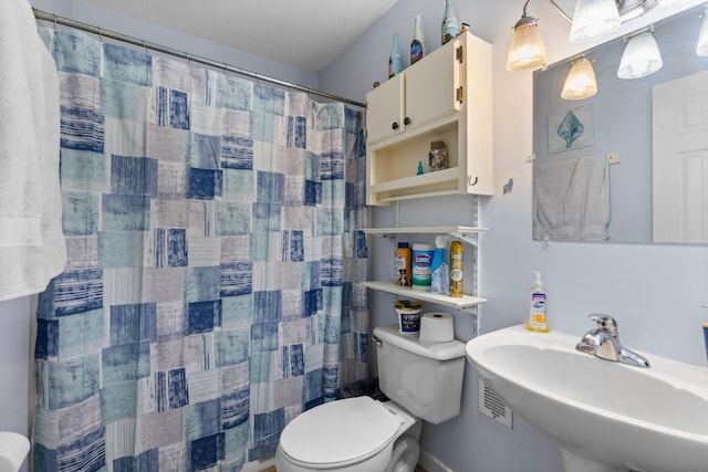 bathroom with curtained shower, toilet, and a sink