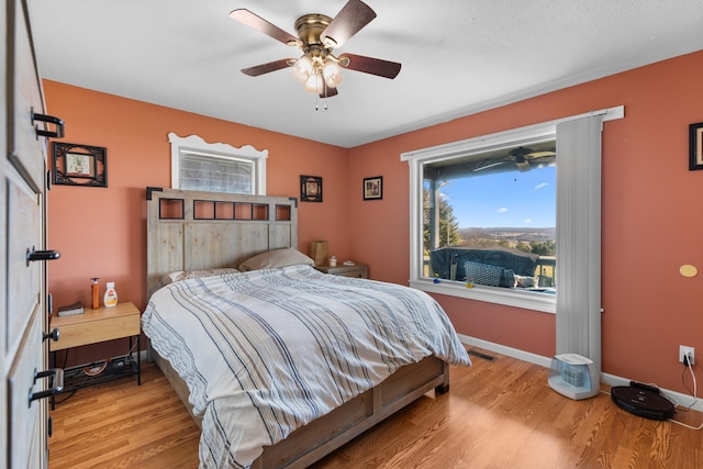 bedroom featuring light wood-type flooring, visible vents, baseboards, and ceiling fan
