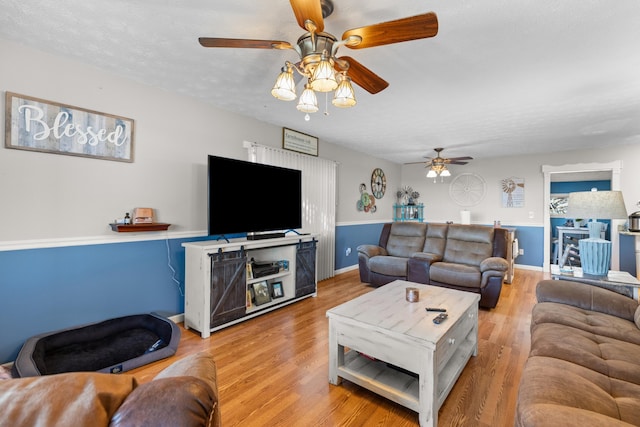living room featuring light wood-type flooring, a ceiling fan, and baseboards