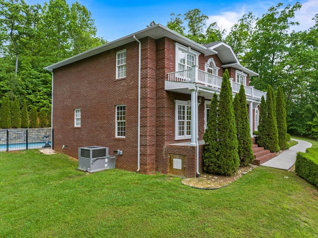 view of home's exterior featuring a balcony, central AC, and brick siding