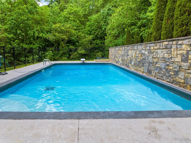 view of pool with fence and a wooded view