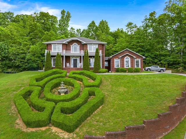 colonial home with a front lawn, a balcony, and brick siding