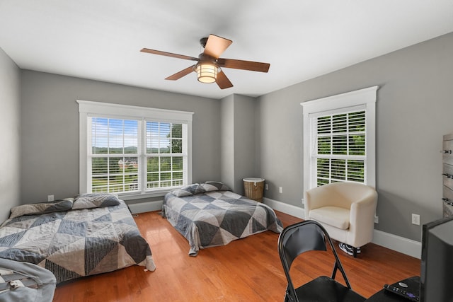 bedroom with wood finished floors, a ceiling fan, and baseboards