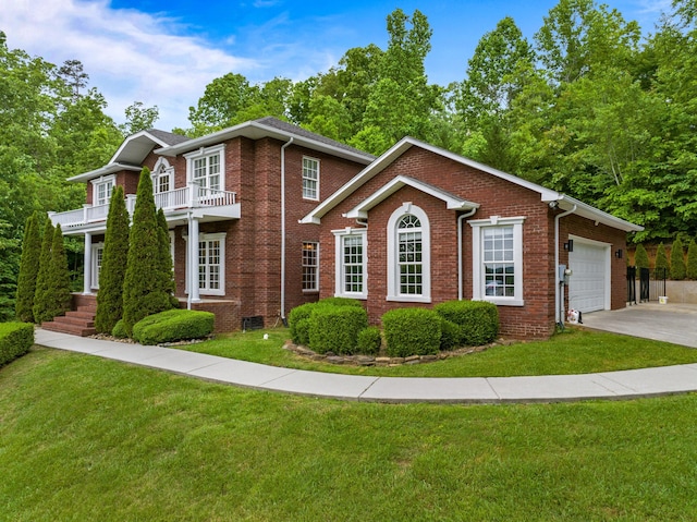 georgian-style home with brick siding, a front lawn, a balcony, and concrete driveway