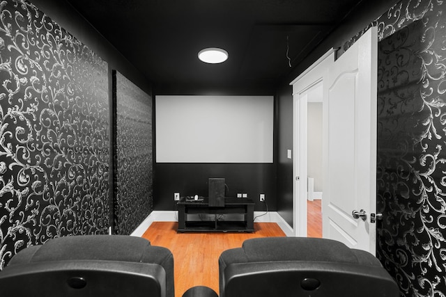 home theater with wood finished floors and wallpapered walls