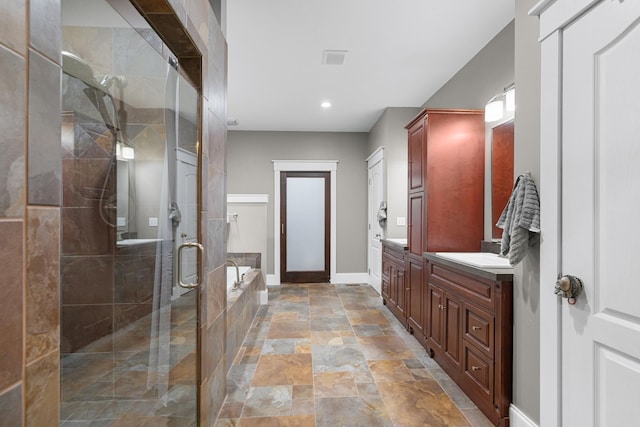 bathroom with baseboards, stone finish floors, a garden tub, a shower stall, and vanity