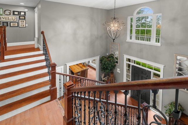 stairs with hardwood / wood-style floors, a chandelier, baseboards, and recessed lighting