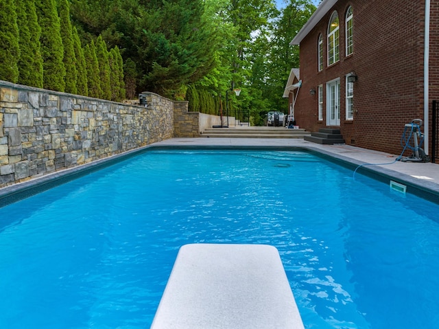 view of swimming pool featuring a diving board and entry steps