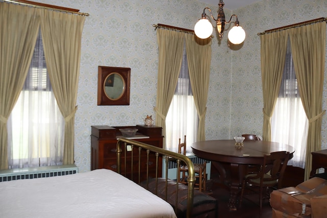 bedroom with radiator heating unit and a notable chandelier