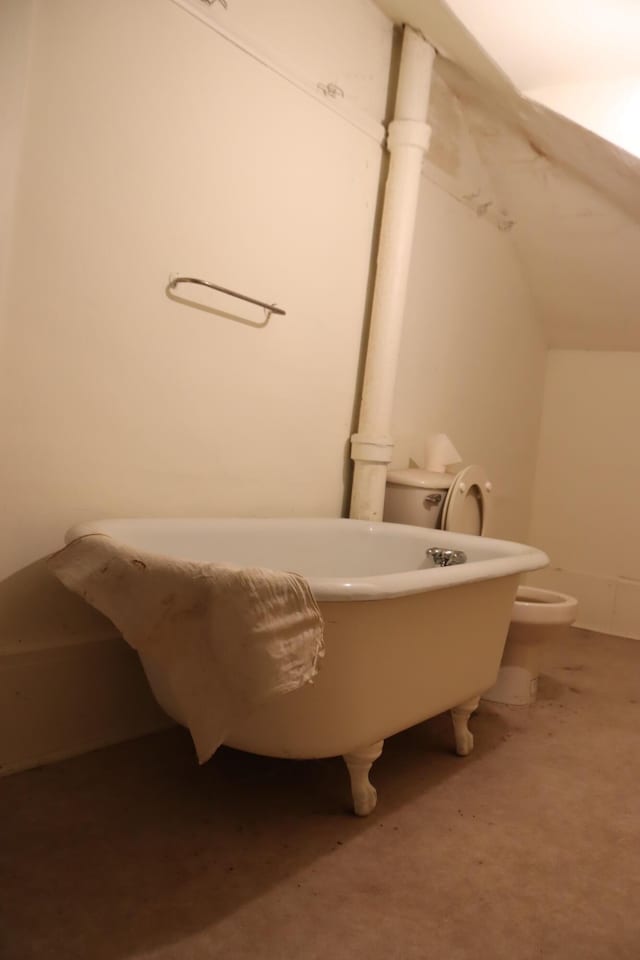 bathroom with a tub to relax in and toilet