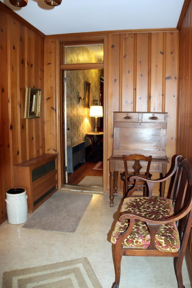 sitting room with ornamental molding and wood walls