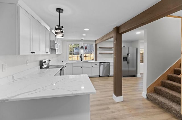 kitchen with light stone countertops, appliances with stainless steel finishes, sink, pendant lighting, and white cabinetry