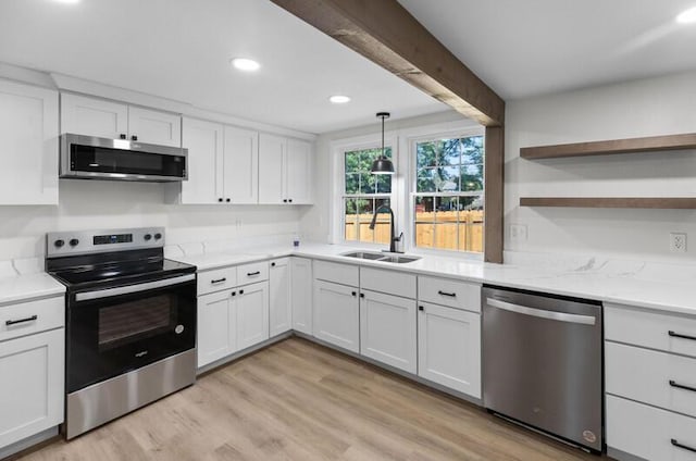 kitchen with white cabinets, light wood-type flooring, sink, and appliances with stainless steel finishes