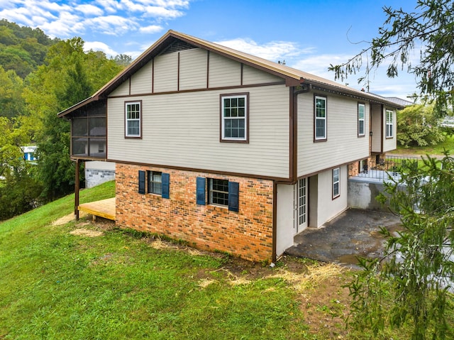 back of property featuring a lawn and a sunroom