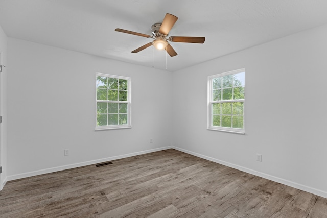 empty room with light hardwood / wood-style floors, a wealth of natural light, and ceiling fan