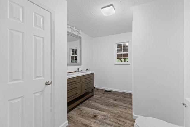 bathroom with hardwood / wood-style flooring, vanity, toilet, and a textured ceiling