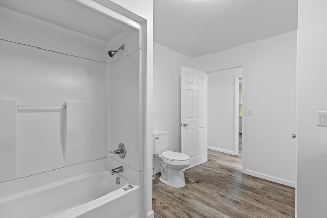 bathroom with bathtub / shower combination, a textured ceiling, hardwood / wood-style flooring, and toilet