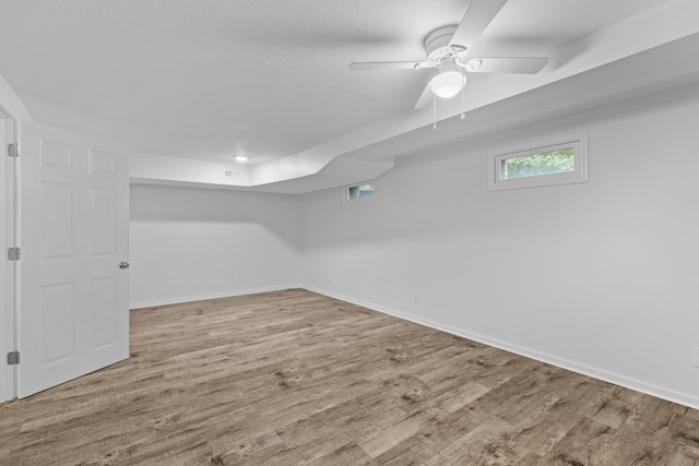 basement featuring ceiling fan and light hardwood / wood-style flooring