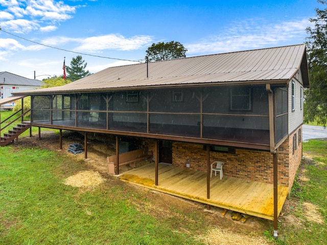 rear view of house featuring a sunroom, a deck, and a lawn