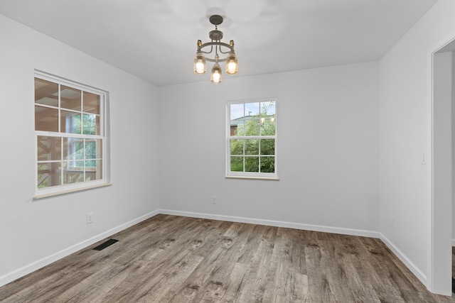 empty room with hardwood / wood-style flooring and a notable chandelier