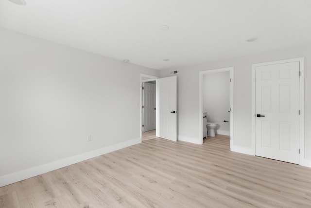 unfurnished bedroom featuring ensuite bathroom and light hardwood / wood-style floors