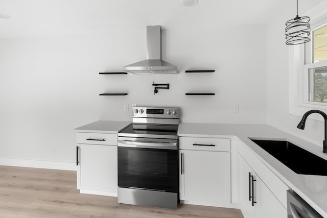 kitchen with decorative light fixtures, sink, white cabinets, stainless steel appliances, and wall chimney exhaust hood