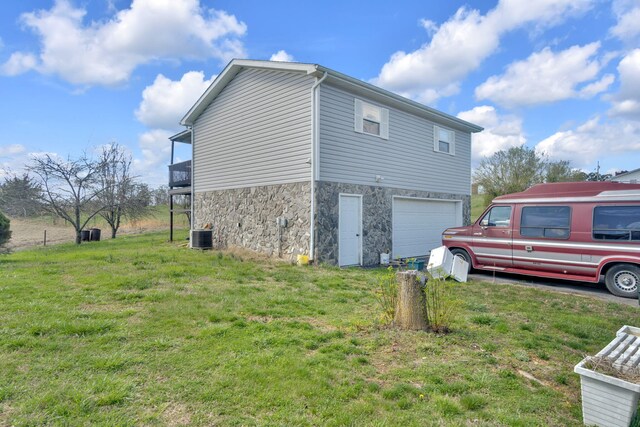 view of side of property with stone siding, a lawn, and an attached garage