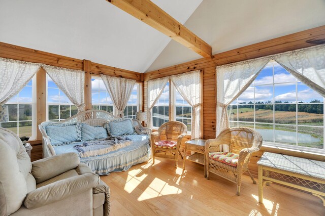 sunroom / solarium featuring a water view and lofted ceiling with beams