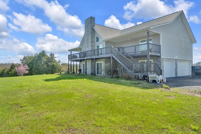 rear view of property with a chimney, a lawn, stairway, a garage, and driveway