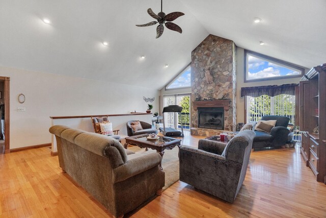 living room featuring plenty of natural light, light hardwood / wood-style floors, a stone fireplace, and high vaulted ceiling