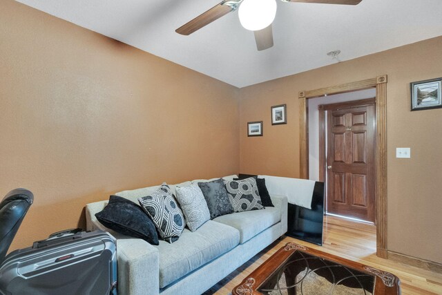 living room featuring wood finished floors, a ceiling fan, and baseboards