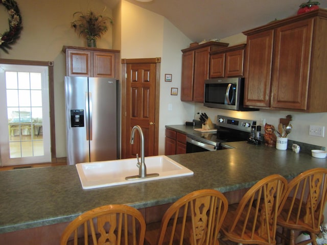 kitchen with lofted ceiling, a breakfast bar, visible vents, appliances with stainless steel finishes, and dark countertops