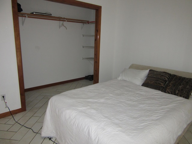 bedroom with a closet, baseboards, and light tile patterned floors