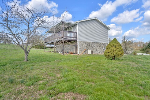 view of side of property with a yard, stone siding, and a wooden deck