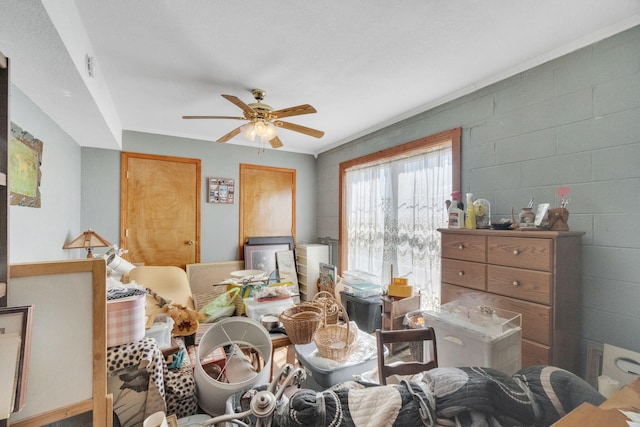 dining area with a ceiling fan and concrete block wall