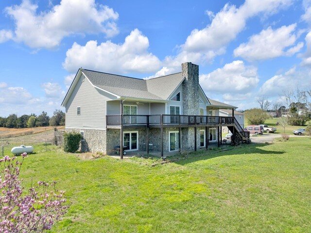 back of property featuring a deck, stone siding, a yard, and a chimney