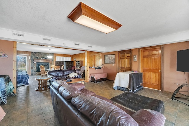 living area featuring a large fireplace, visible vents, and a textured ceiling