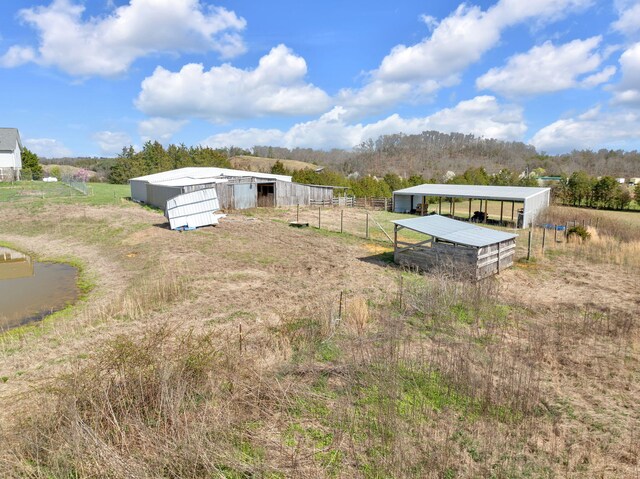 view of yard featuring fence, a pole building, an outbuilding, and a rural view