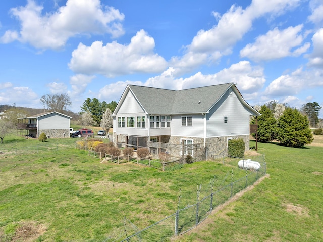 rear view of property featuring stone siding, fence, and a lawn