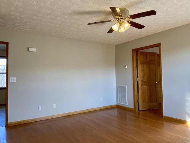 empty room featuring ceiling fan, hardwood / wood-style flooring, and a textured ceiling