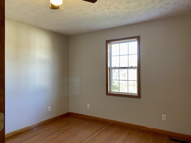 spare room featuring hardwood / wood-style flooring, ceiling fan, and a textured ceiling