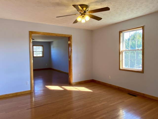 empty room with ceiling fan, hardwood / wood-style floors, and a textured ceiling