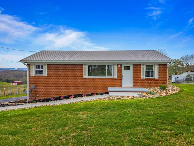 ranch-style house featuring a front lawn, metal roof, and brick siding