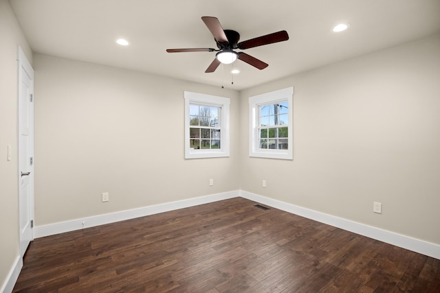 empty room featuring dark wood-style flooring, recessed lighting, baseboards, and visible vents