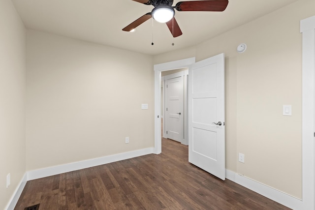 spare room with baseboards, ceiling fan, and dark wood-style flooring