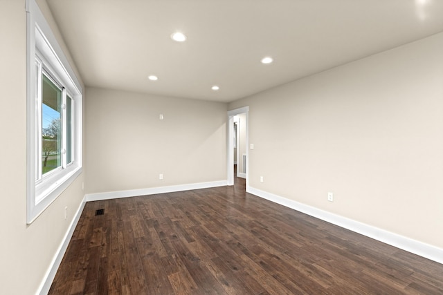 unfurnished room featuring dark wood-style flooring, visible vents, baseboards, and recessed lighting