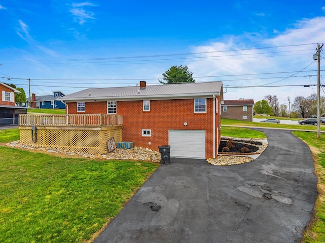 back of property featuring driveway, metal roof, a garage, and brick siding
