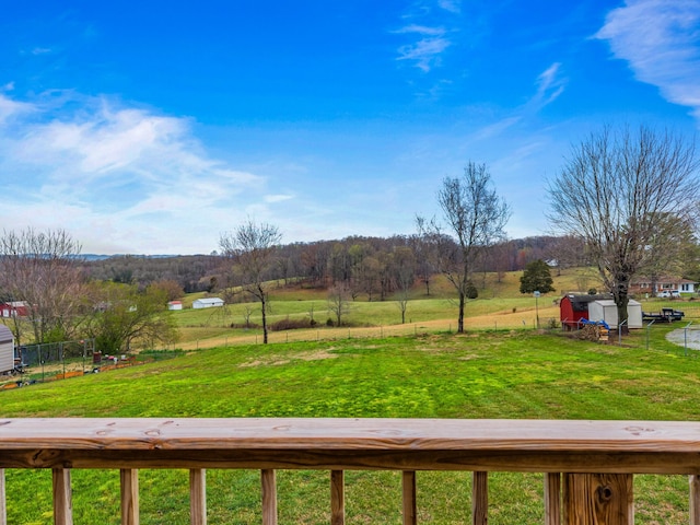 view of yard featuring fence, a rural view, and a wooded view