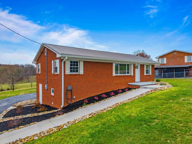 view of front of house with metal roof, fence, a front lawn, and brick siding
