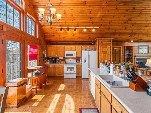 702 John Sevier Dr, Sevierville, TN 37876 - kitchen featuring white appliances, a chandelier, light countertops, a sink, and wooden walls